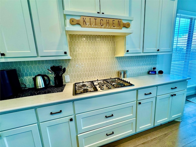 kitchen featuring hardwood / wood-style flooring, white cabinetry, stainless steel gas cooktop, and tasteful backsplash