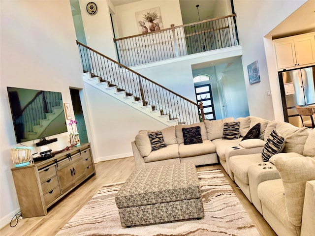 living room with light hardwood / wood-style flooring and a towering ceiling