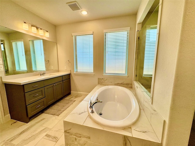 bathroom featuring a relaxing tiled tub and vanity