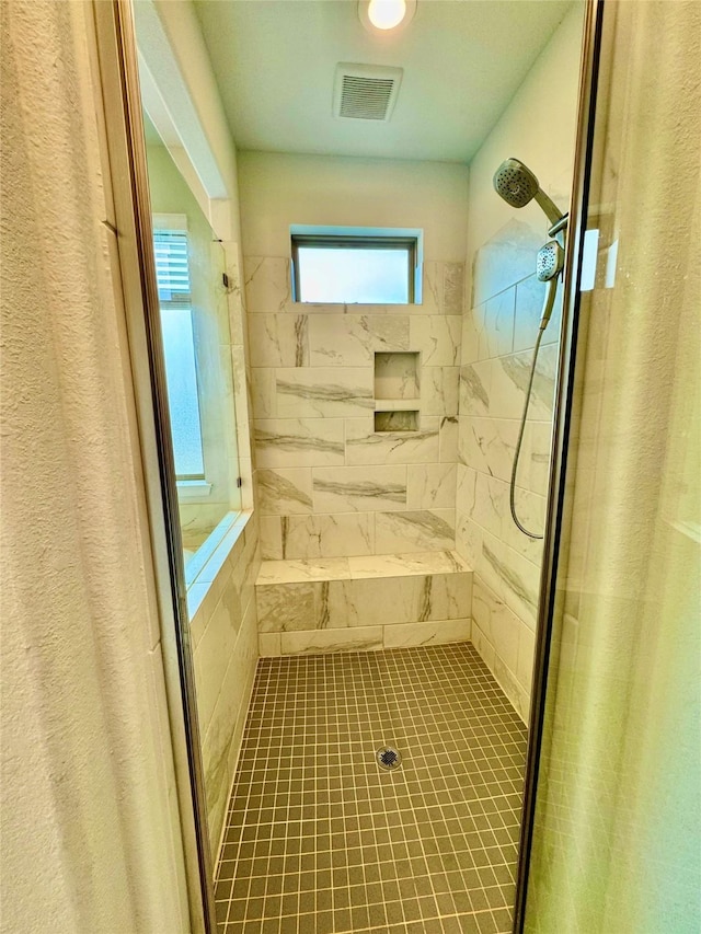 bathroom featuring tiled shower and tile patterned flooring