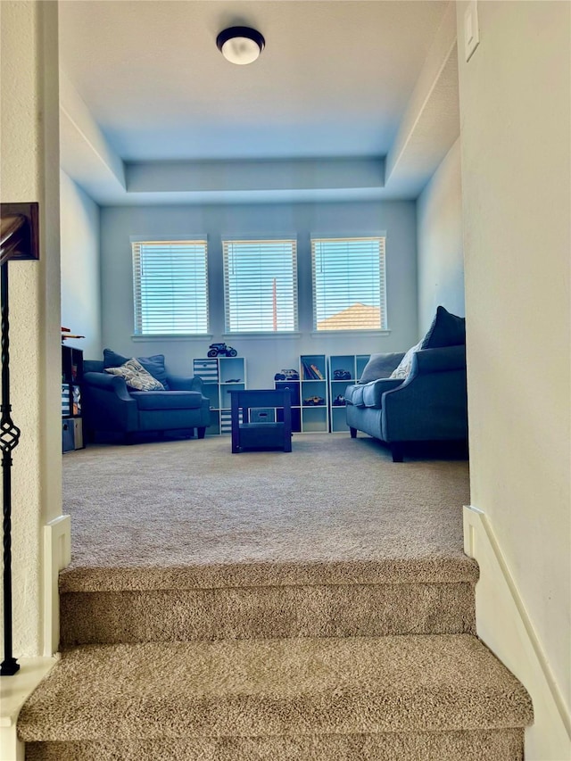 staircase featuring a healthy amount of sunlight, a raised ceiling, and carpet floors