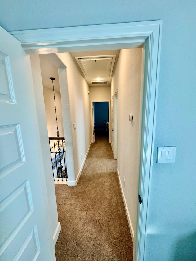 hallway with carpet floors and a notable chandelier