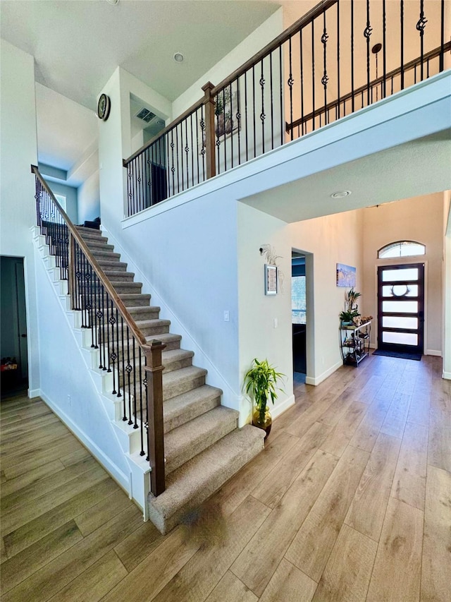 stairs featuring a high ceiling and wood-type flooring