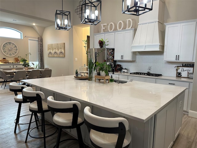 kitchen with white cabinetry, stainless steel appliances, a large island, and light stone counters