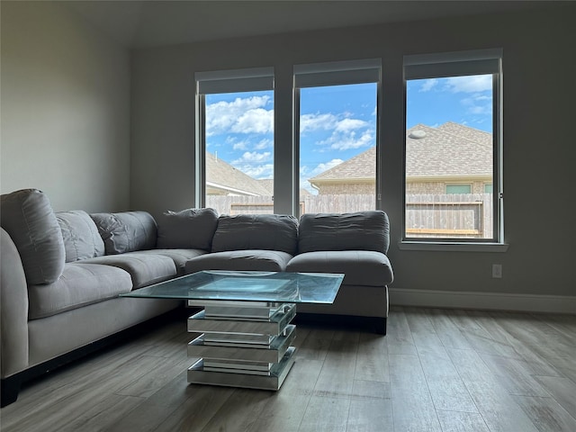 living area with a healthy amount of sunlight, baseboards, and wood finished floors