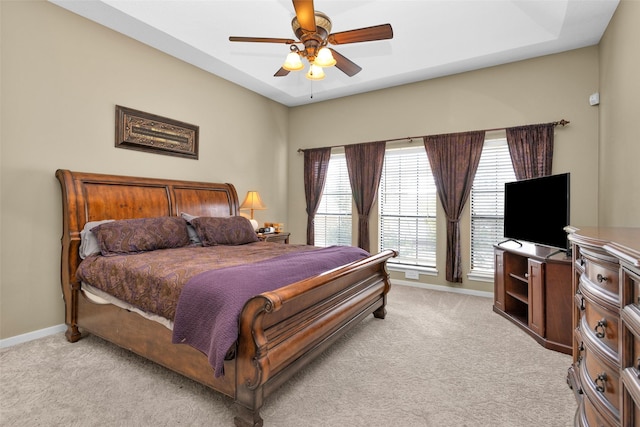 carpeted bedroom with ceiling fan and a raised ceiling