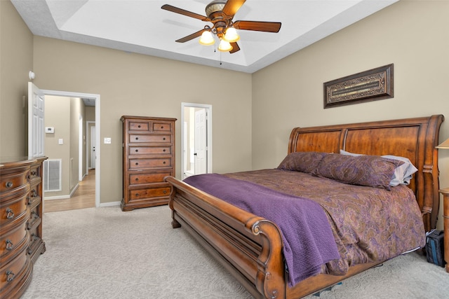 bedroom with light carpet, a tray ceiling, and ceiling fan