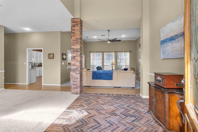 interior space featuring ceiling fan, ornamental molding, wood-type flooring, and ornate columns