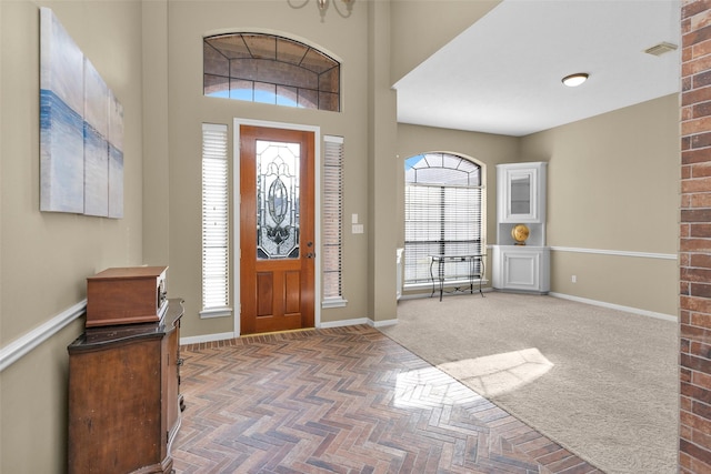 entryway with dark colored carpet and a high ceiling