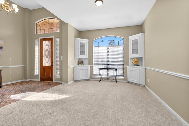 carpeted foyer entrance featuring a chandelier