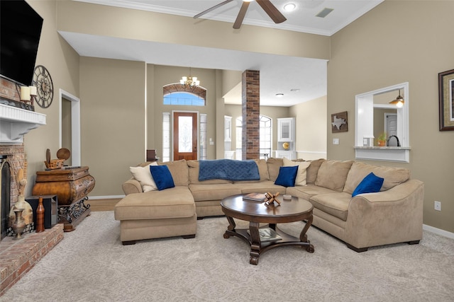 living room with ornate columns, crown molding, ceiling fan with notable chandelier, and a fireplace