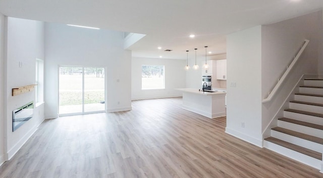 unfurnished living room featuring sink, heating unit, and light wood-type flooring