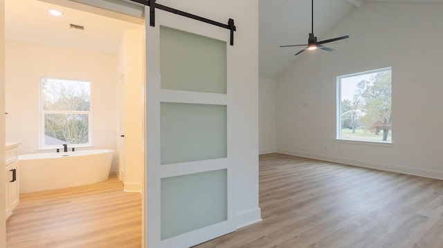 interior space with ceiling fan, vanity, lofted ceiling, hardwood / wood-style floors, and a bath