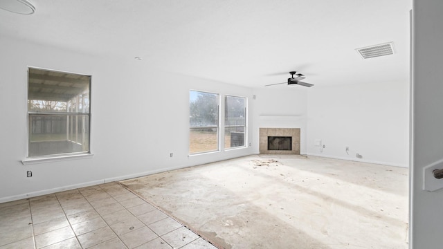 unfurnished living room with ceiling fan and a tiled fireplace