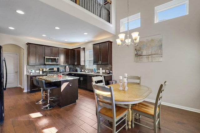 kitchen featuring a kitchen island, a breakfast bar, hanging light fixtures, stainless steel appliances, and light stone countertops