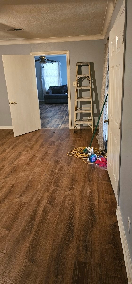 hall with wood-type flooring, a textured ceiling, and crown molding