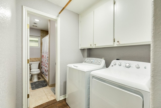 washroom featuring dark tile patterned floors, independent washer and dryer, and cabinets