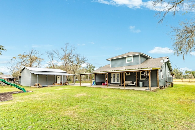 rear view of house featuring a patio area, an outdoor structure, a yard, and a playground