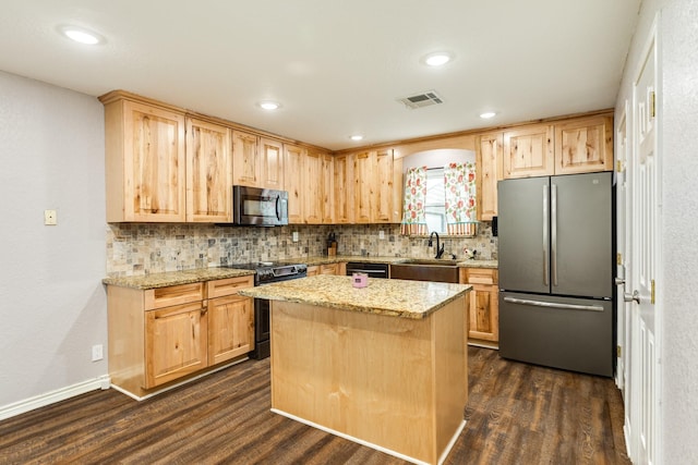 kitchen with appliances with stainless steel finishes, a center island, dark hardwood / wood-style flooring, light stone countertops, and sink