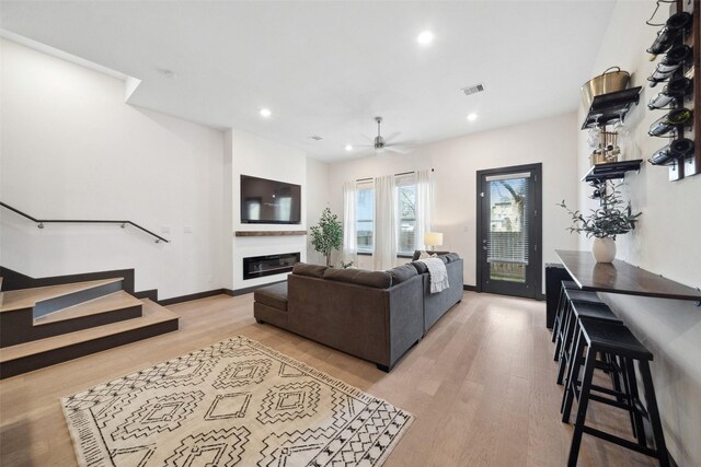 living room with ceiling fan, visible vents, a glass covered fireplace, recessed lighting, and light wood-style flooring