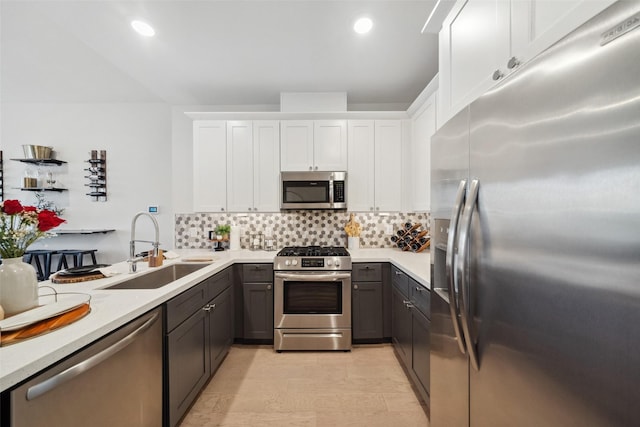 kitchen with white cabinetry, stainless steel appliances, decorative backsplash, sink, and gray cabinetry