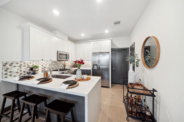 kitchen with white cabinets, kitchen peninsula, a kitchen breakfast bar, and stainless steel appliances