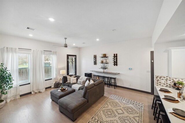 living room with a ceiling fan, visible vents, baseboards, light wood-style floors, and recessed lighting