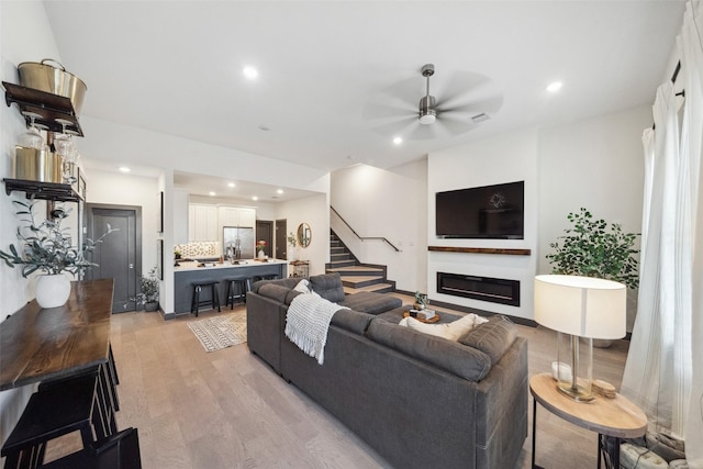 living room with ceiling fan and light wood-type flooring