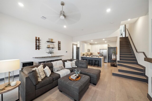 living area with stairs, ceiling fan, visible vents, and light wood-type flooring