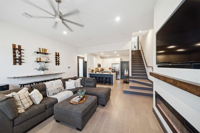 living room with ceiling fan, light wood-style flooring, stairs, recessed lighting, and visible vents
