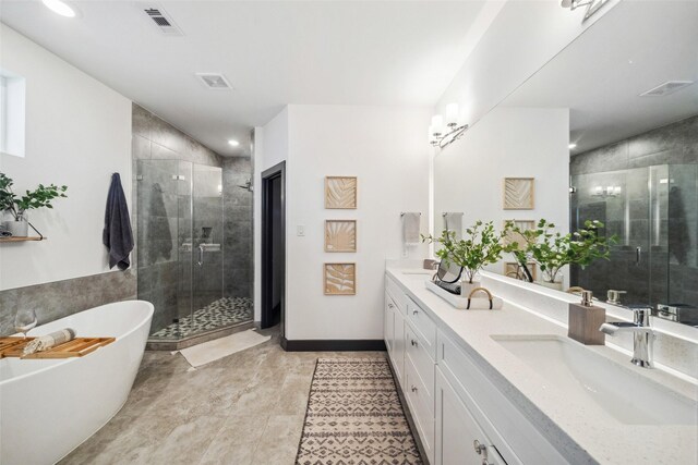 bathroom with visible vents, double vanity, a freestanding tub, and a shower stall