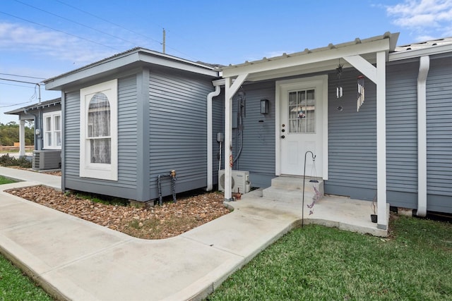 doorway to property featuring a lawn and central AC