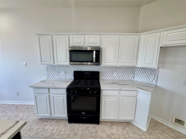 kitchen with decorative backsplash, light stone countertops, white cabinets, and black range with gas stovetop