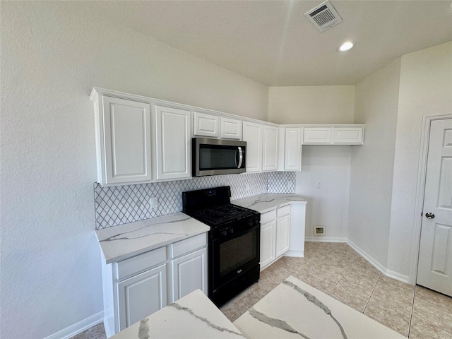 kitchen featuring white cabinetry, tasteful backsplash, light tile patterned flooring, light stone countertops, and black gas stove