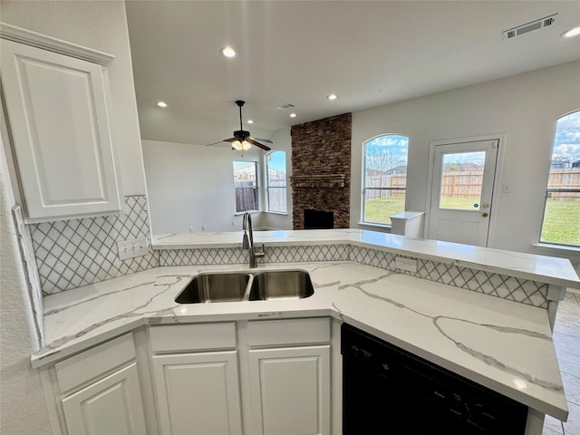 kitchen with white cabinets, black dishwasher, sink, backsplash, and kitchen peninsula