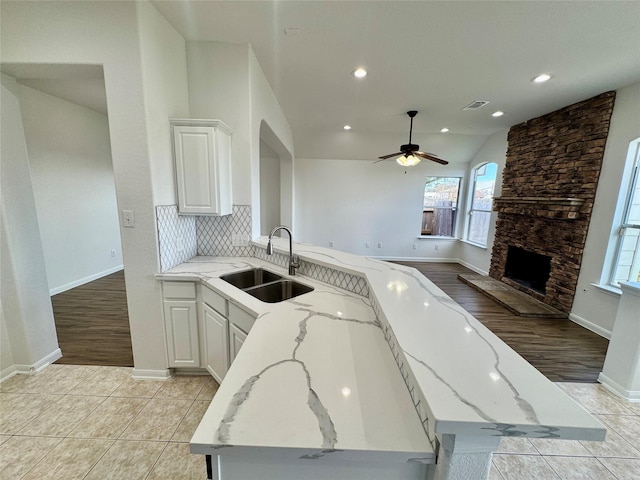 kitchen with ceiling fan, light stone countertops, white cabinets, and sink