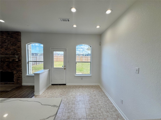 interior space featuring light tile patterned flooring and a stone fireplace