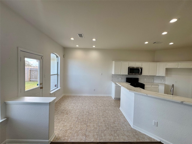 kitchen featuring light tile patterned floors, white cabinetry, decorative backsplash, and range