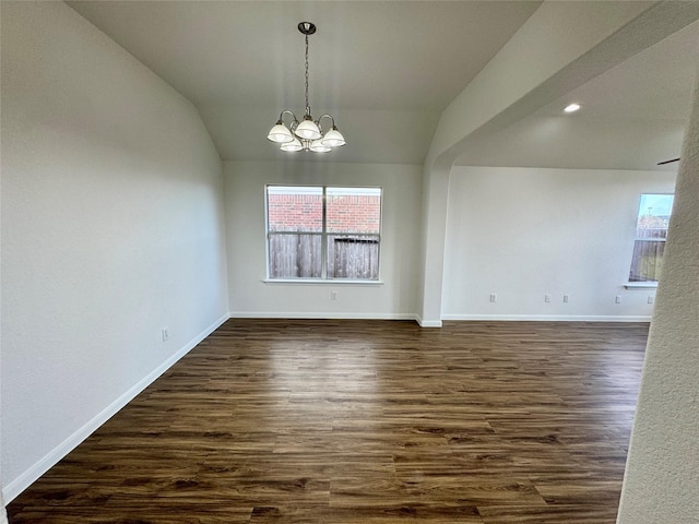 unfurnished dining area featuring dark wood-type flooring, a notable chandelier, and vaulted ceiling