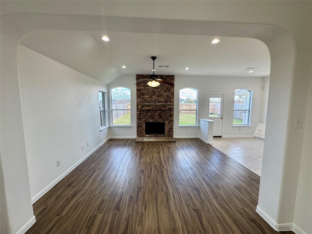 unfurnished living room featuring vaulted ceiling, dark hardwood / wood-style floors, ceiling fan, and a fireplace