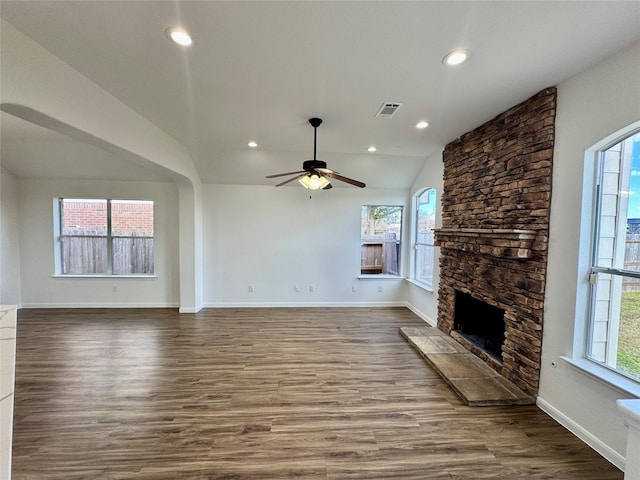 unfurnished living room featuring vaulted ceiling, ceiling fan, hardwood / wood-style flooring, and a stone fireplace