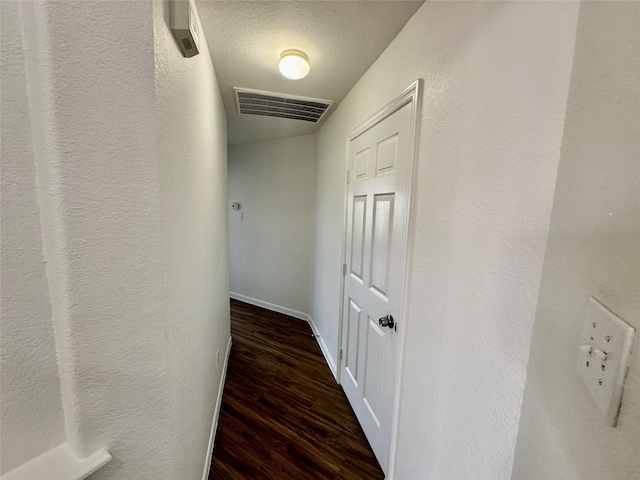 hallway with dark hardwood / wood-style floors and a textured ceiling