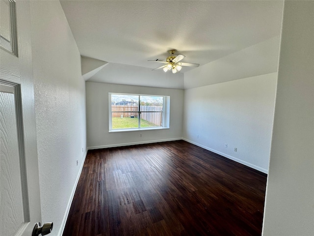 spare room with ceiling fan, dark hardwood / wood-style floors, and vaulted ceiling