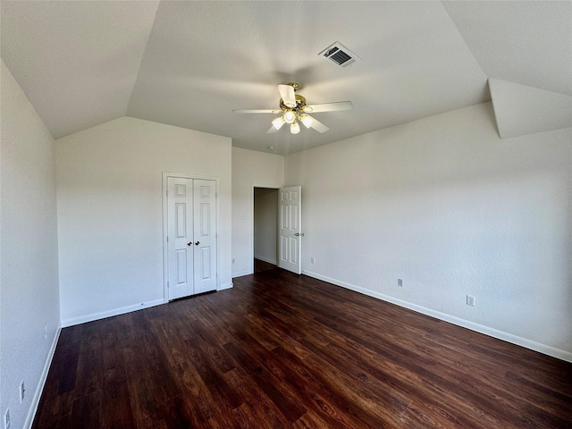 unfurnished bedroom featuring ceiling fan, dark hardwood / wood-style flooring, lofted ceiling, and a closet