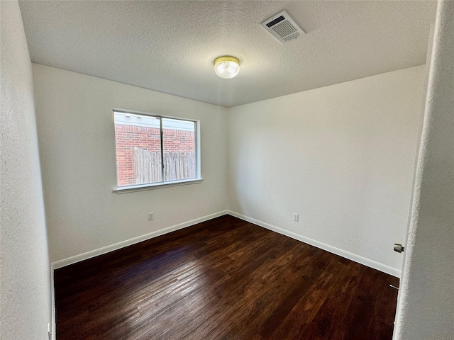 unfurnished room featuring a textured ceiling and dark hardwood / wood-style floors