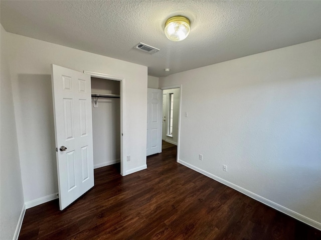 unfurnished bedroom with a closet, dark wood-type flooring, and a textured ceiling