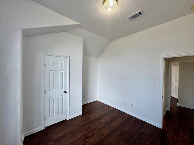 bonus room with a textured ceiling, lofted ceiling, and dark hardwood / wood-style floors