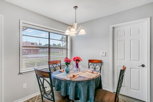 dining room with hardwood / wood-style floors, a wealth of natural light, a textured ceiling, and a chandelier