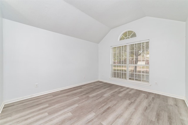 unfurnished room with vaulted ceiling and light wood-type flooring