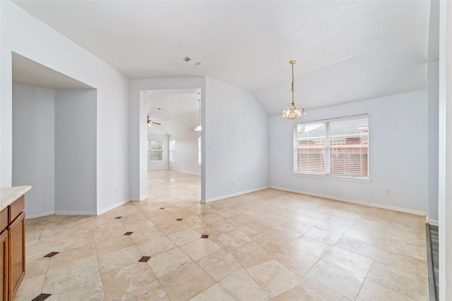 spare room with vaulted ceiling and ceiling fan with notable chandelier